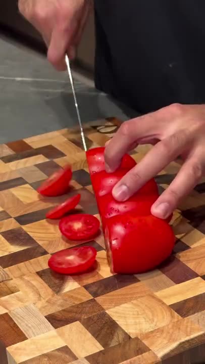 The Notorious Damascus chef's knife slicing a tomato